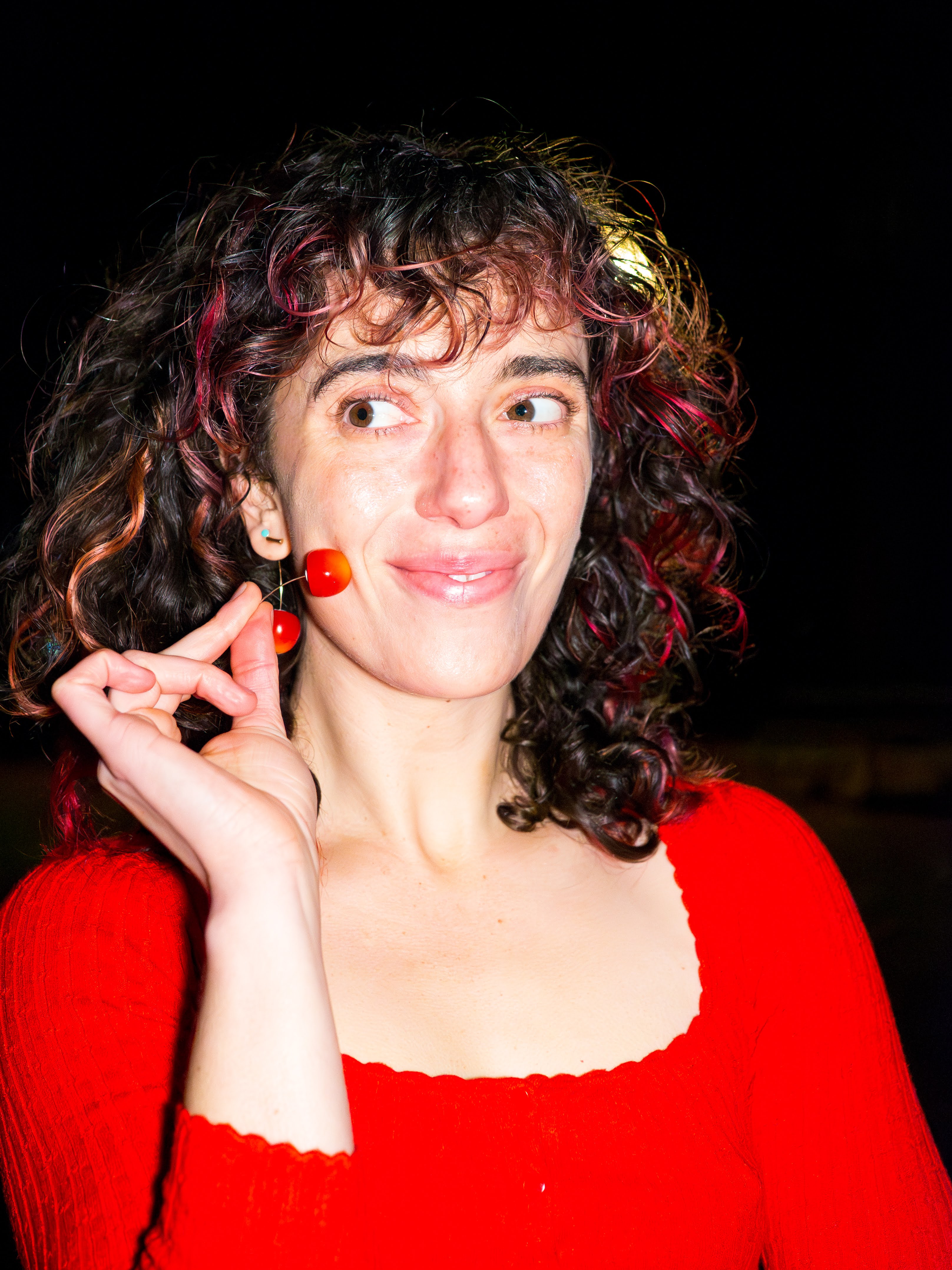 Lucy holding a cherry in a playful portrait